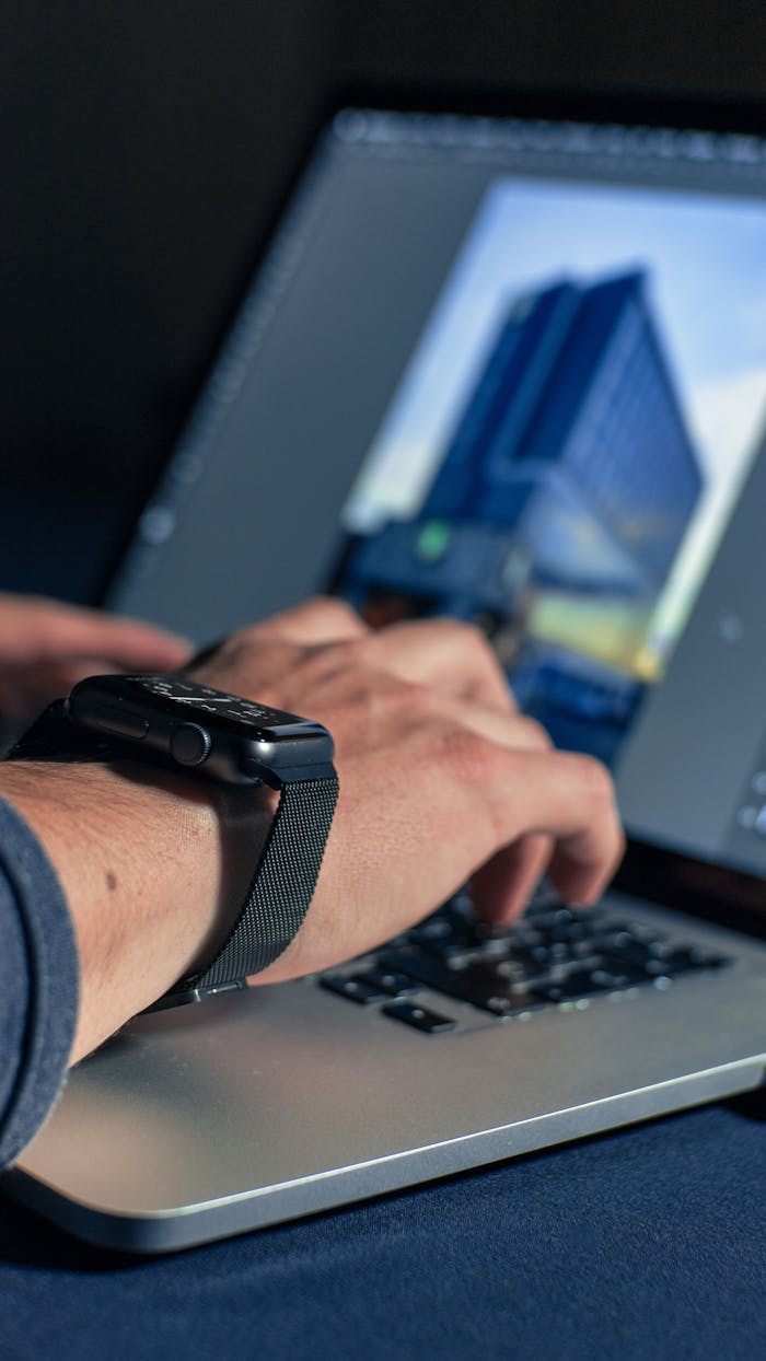 Detail shot of hands typing on a laptop with a smartwatch in view, perfect for tech themes.